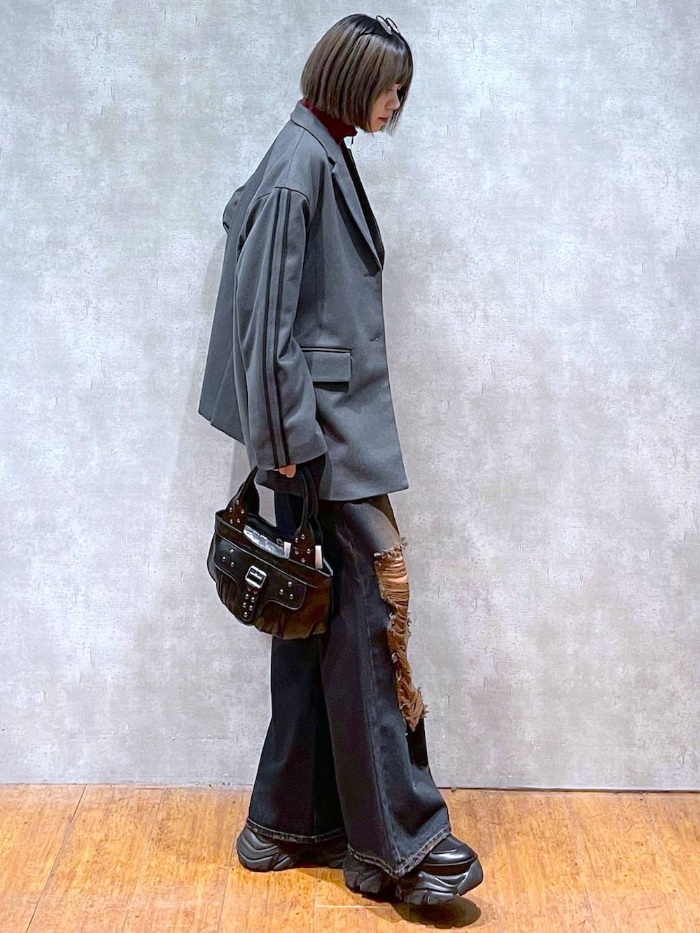 ブラック系のスニーカー、レッド系のニット/セーター、ブラック系のハンドバッグを着用したレディースの秋コーディネートの4枚目の写真