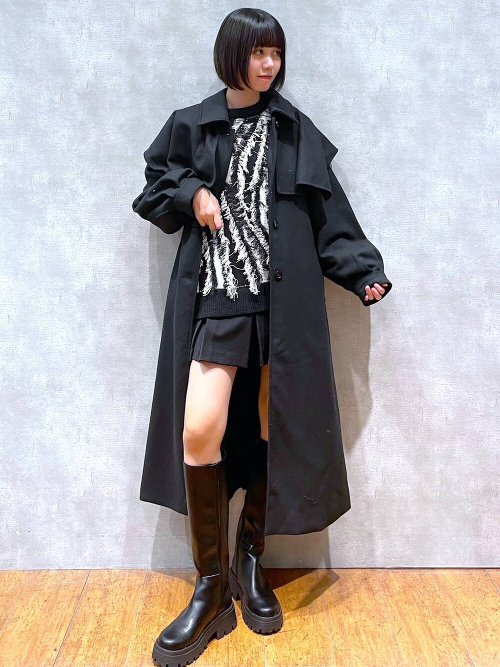 ブラック系のチェスターコート、ブラック系のブーツ、ブラック系のニット/セーターを着用したレディースの冬コーディネートの5枚目の写真