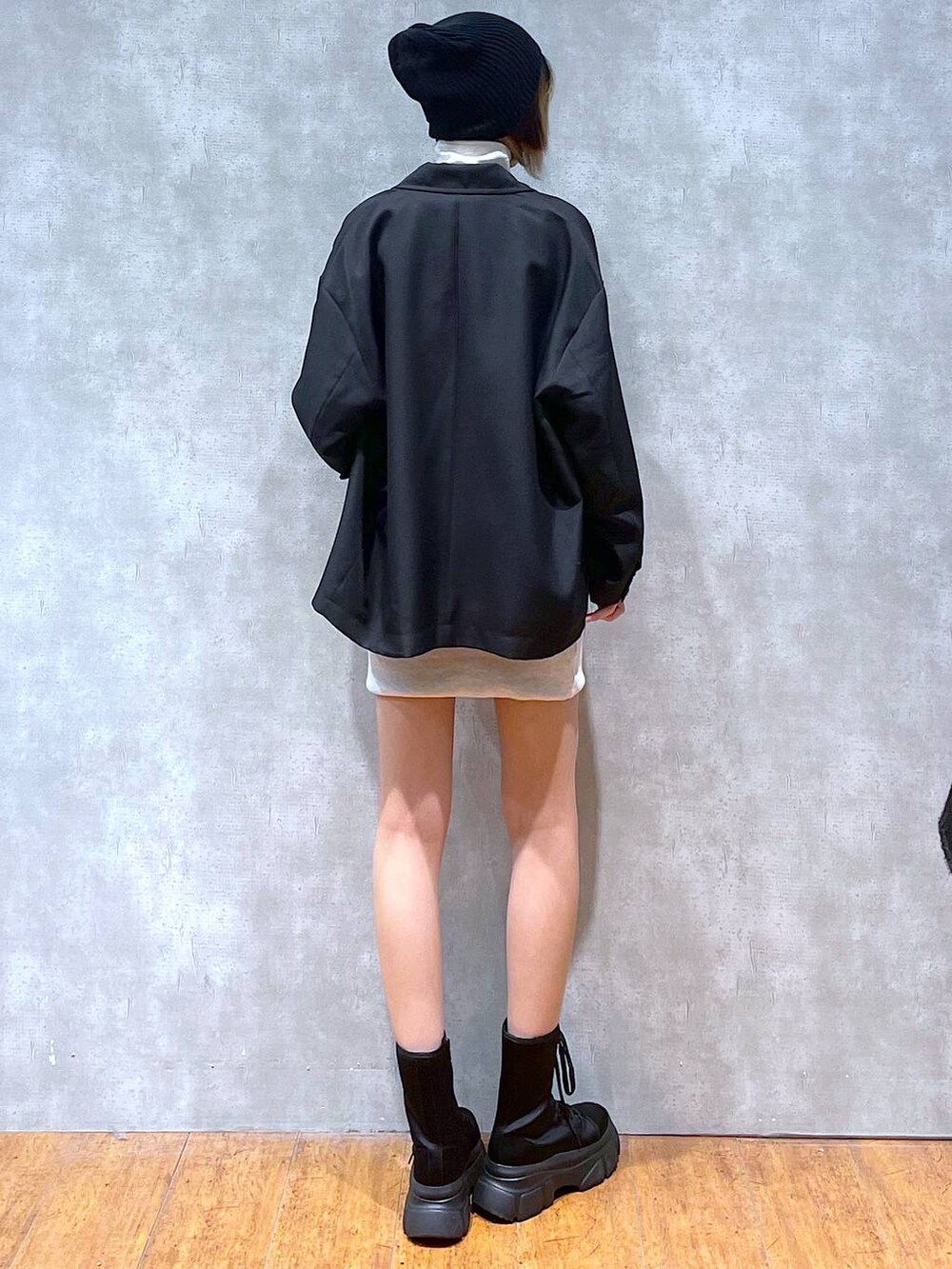 ブラック系のテーラードジャケット、ベージュ系のワンピース、ブラック系のブーツを着用したレディースの冬コーディネートの4枚目の写真