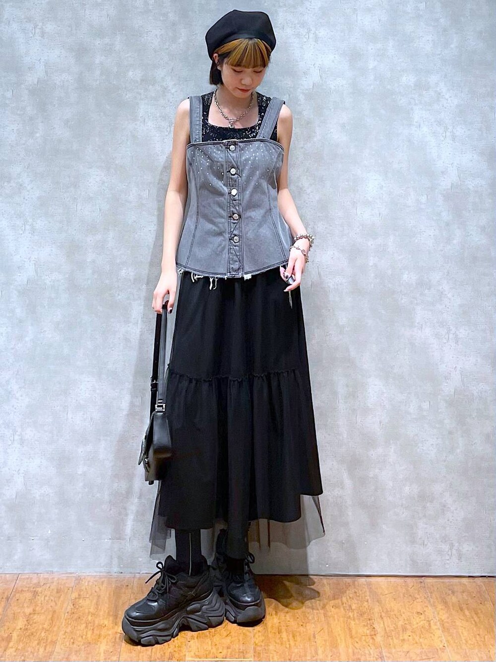 ブラック系のスニーカー、ブラック系のハンドバッグ、ブラック系のスカートを着用したレディースの夏コーディネートの2枚目の写真