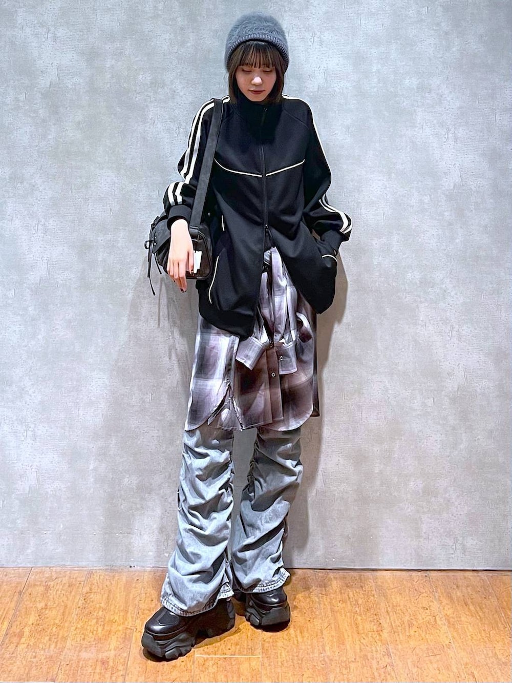 ブラック系のスニーカー、ブラック系のショルダーバッグ、ブルー系のデニムパンツを着用したレディースの秋コーディネートの6枚目の写真