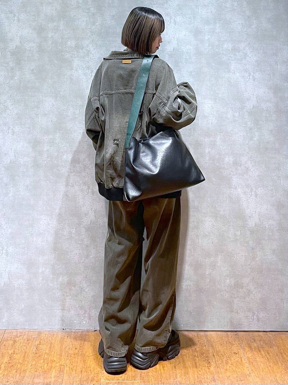 ブラック系のスニーカー、ブラック系のデニムパンツ、ブラック系のブルゾンを着用したレディースの秋コーディネートの3枚目の写真