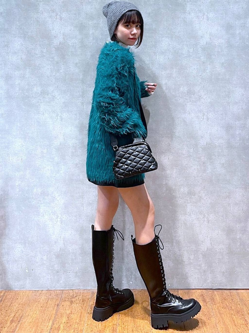 グリーン系のカーディガン/ボレロ、ホワイト系のニット/セーター、ブラック系のブーツを着用したレディースの冬コーディネートの2枚目の写真