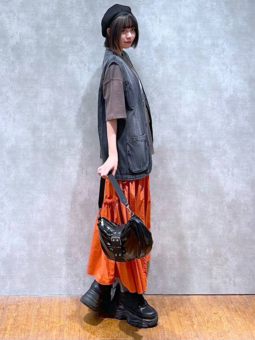 ブラック系のスニーカー、ブラック系のショルダーバッグ、オレンジ系のスカートを着用したレディースの夏コーディネートの2枚目の写真