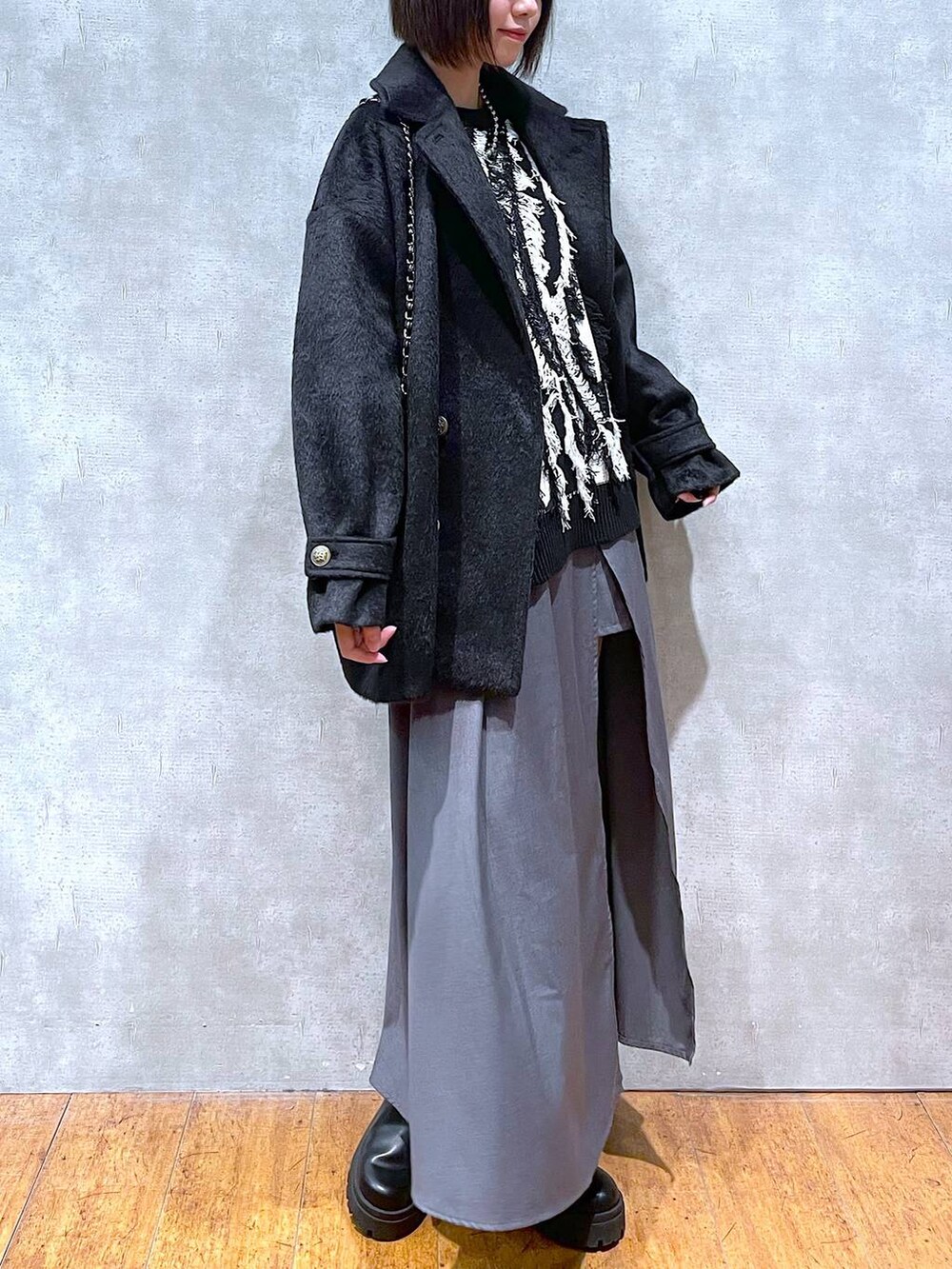 ブラック系のブーツ、グレー系のスカート、ブラック系のニット/セーターを着用したレディースの冬コーディネートの2枚目の写真