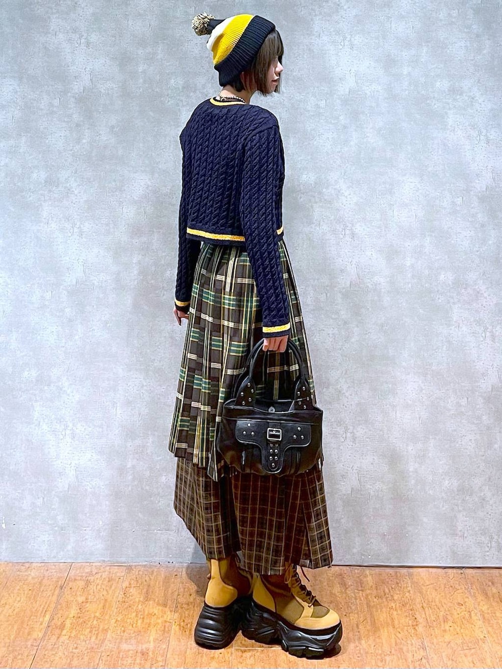 ブラウン系のブーツ、イエロー系のスカート、ブラック系のハンドバッグを着用したレディースの秋コーディネートの9枚目の写真