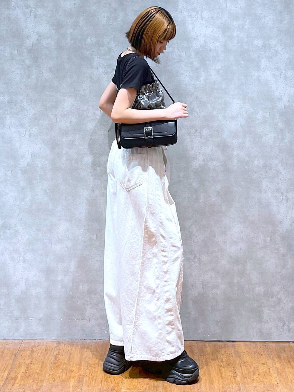 ブラック系のスニーカー、ホワイト系のデニムパンツ、ブラック系のハンドバッグを着用したレディースの夏コーディネートの2枚目の写真