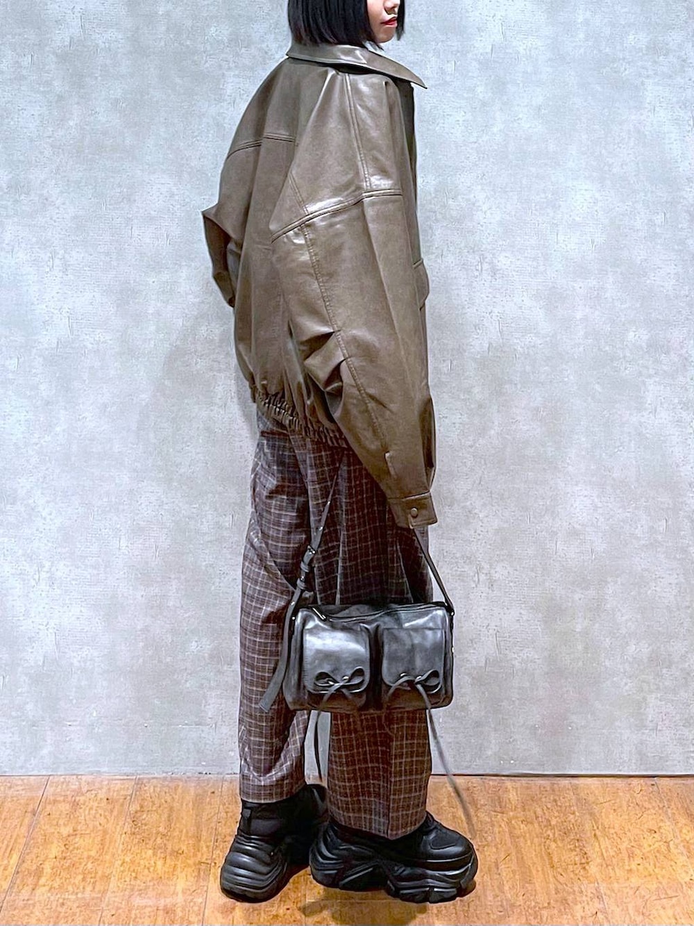 ブラック系のスニーカー、ブラック系のショルダーバッグ、ブラウン系のブルゾンを着用したレディースの秋コーディネートの5枚目の写真