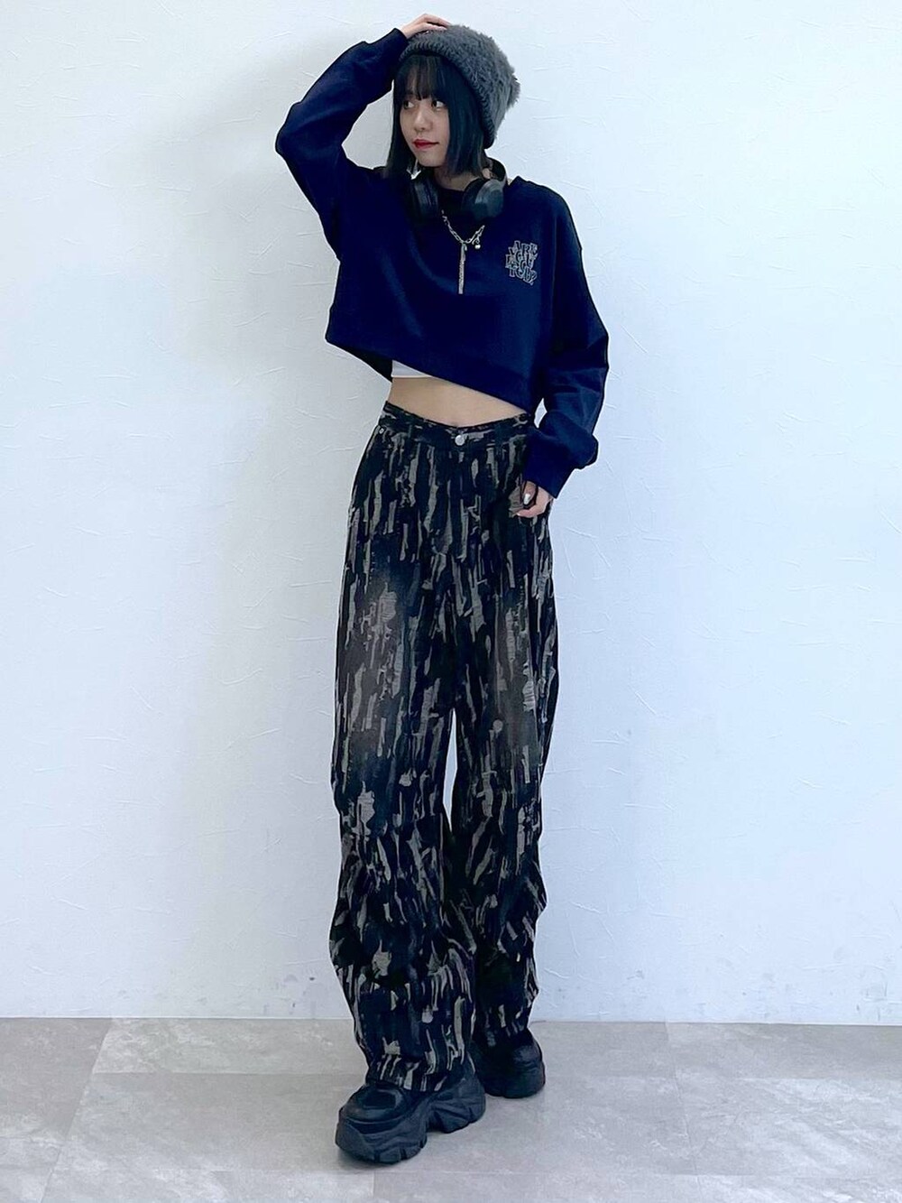 ブラック系のスニーカー、ブラック系のデニムパンツ、ホワイト系のキャミソールを着用したレディースの秋コーディネートの2枚目の写真