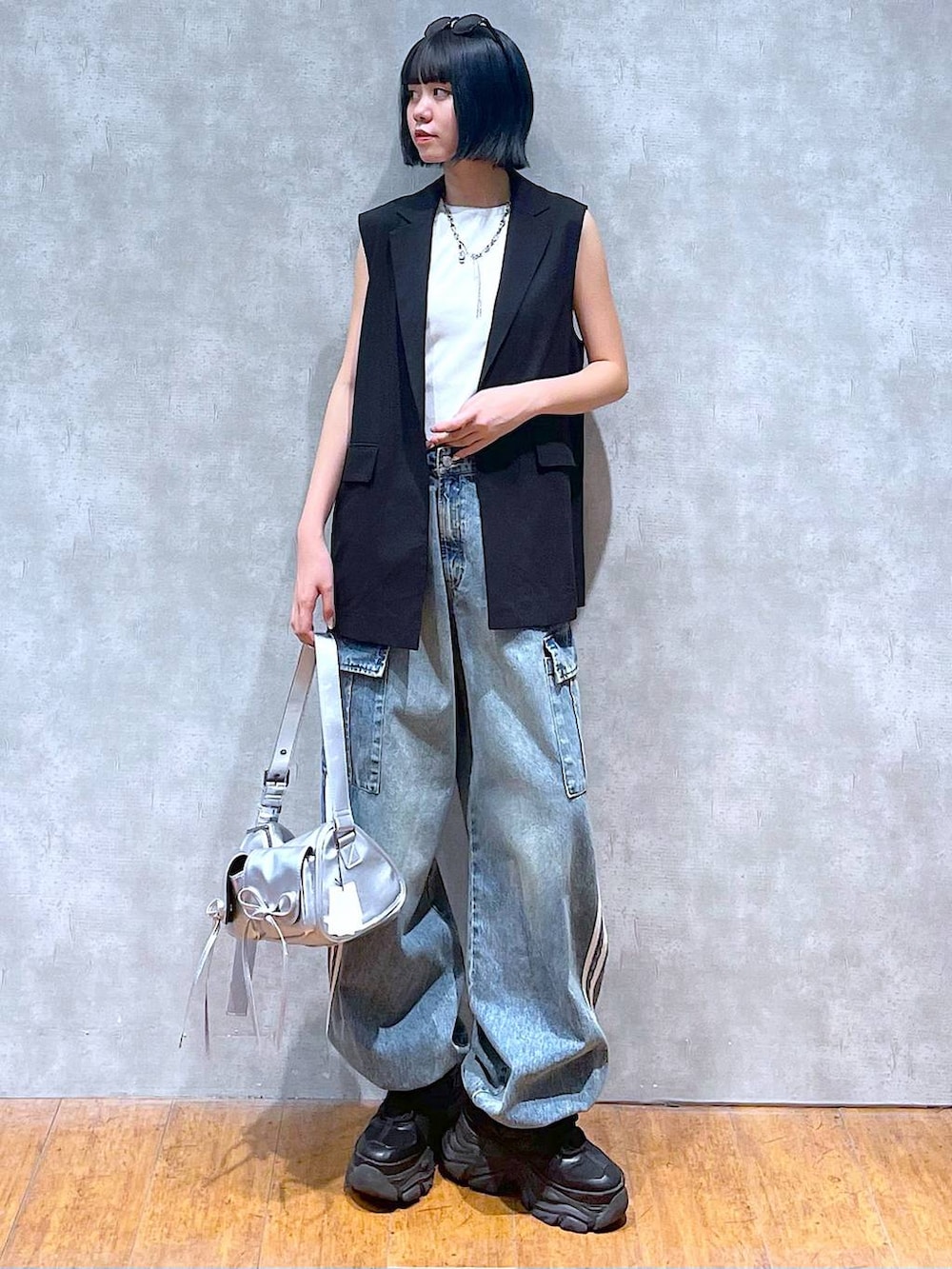 ブラック系のスニーカー、ブルー系のデニムパンツ、ホワイト系のタンクトップを着用したレディースの夏コーディネートの5枚目の写真