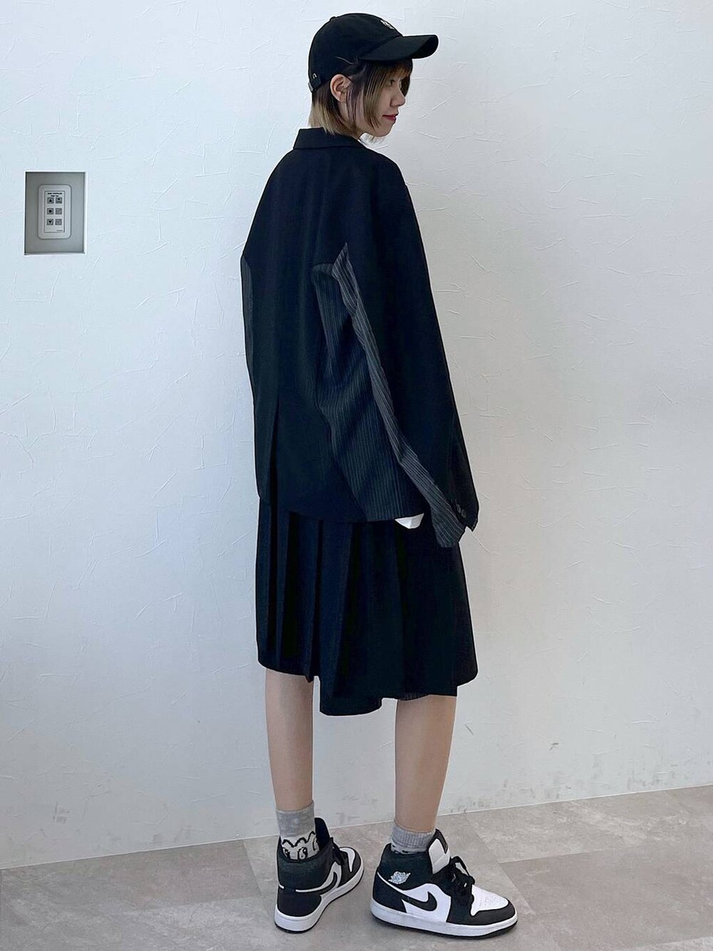 ブラック系のテーラードジャケット、ブラック系のスラックス、ブラック系のキャップを着用したレディースの冬コーディネートの4枚目の写真