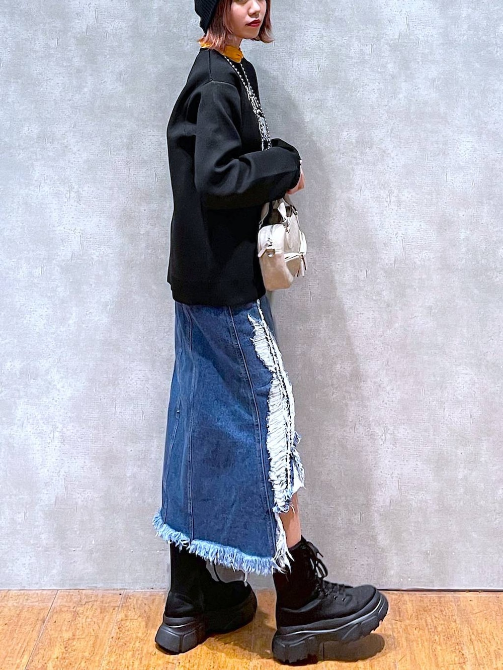 オレンジ系のTシャツ/カットソー、ブラック系のニット/セーター、ベージュ系のボストンバッグを着用したレディースの春コーディネートの3枚目の写真