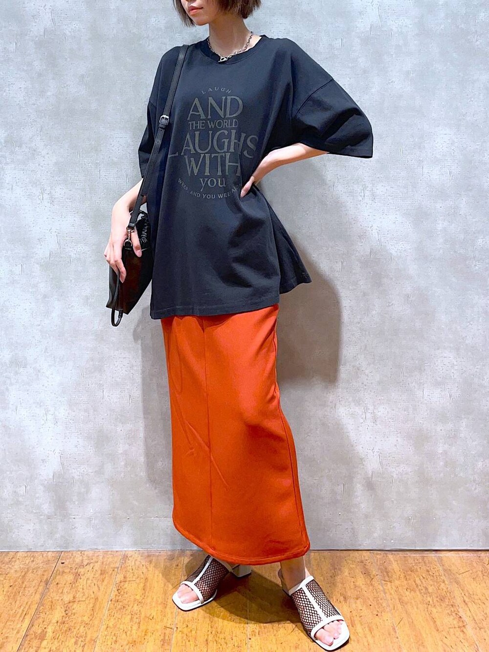 ホワイト系のサンダル、オレンジ系のスカート、ブラック系のショルダーバッグを着用したレディースの夏コーディネートの2枚目の写真