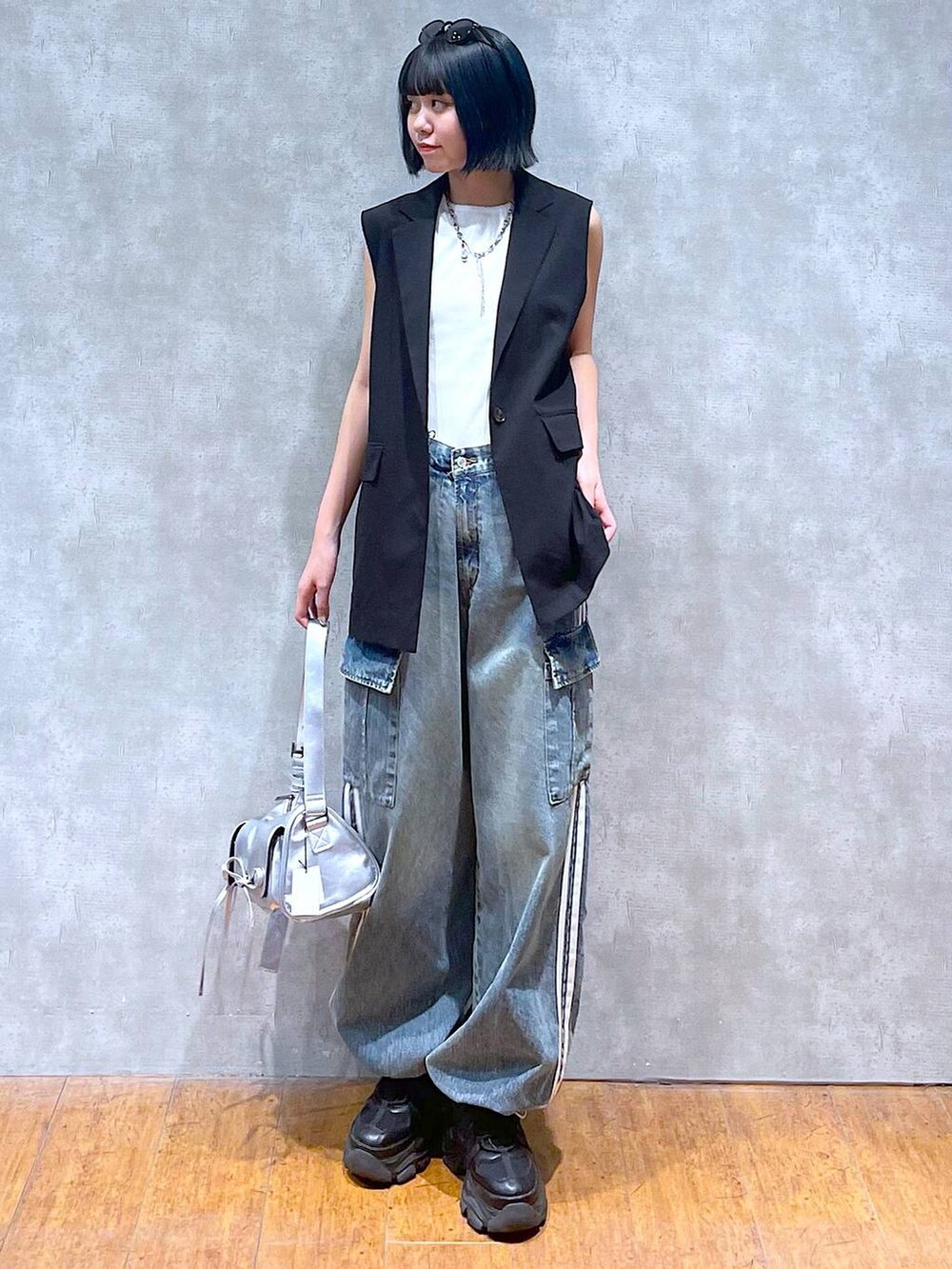 ブラック系のスニーカー、ブルー系のデニムパンツ、ホワイト系のタンクトップを着用したレディースの夏コーディネートの2枚目の写真