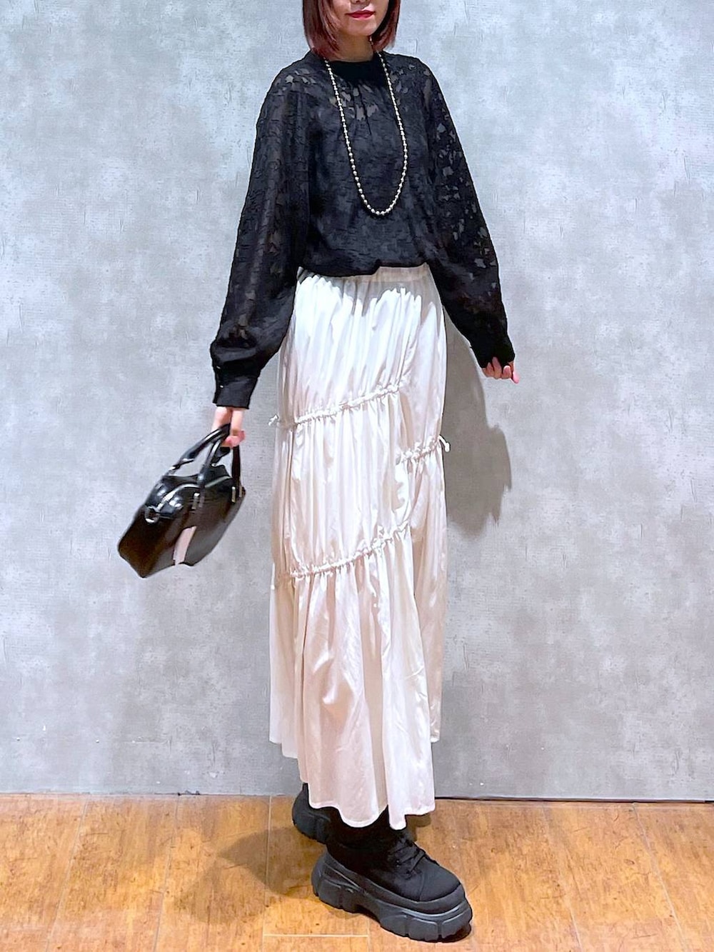 ブラック系のシャツ/ブラウス、ホワイト系のスカート、ブラック系のボストンバッグを着用したレディースの春コーディネートの4枚目の写真