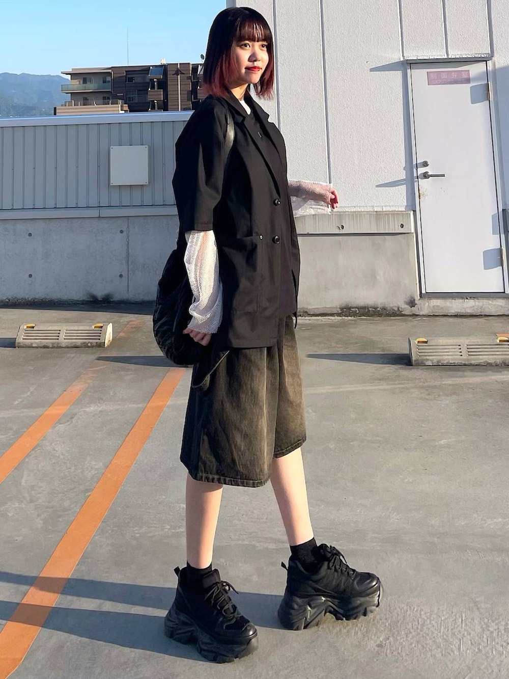 ブラック系のショルダーバッグ、ブラック系のスニーカー、ホワイト系のTシャツ/カットソーを着用したレディースの春コーディネートの6枚目の写真