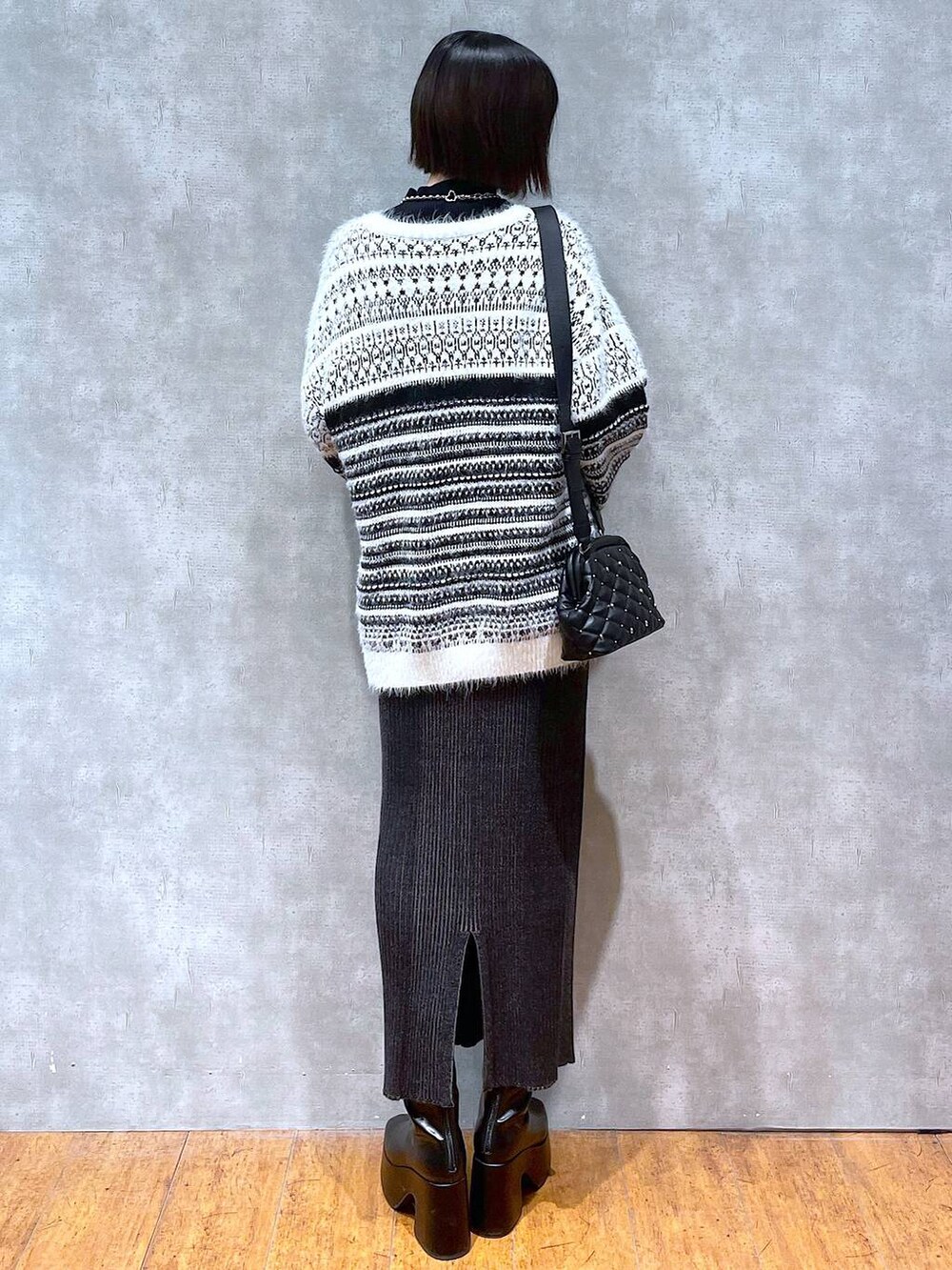 ブラック系のニット/セーター、ブラック系のブーツ、ブラック系のショルダーバッグを着用したレディースの冬コーディネートの5枚目の写真