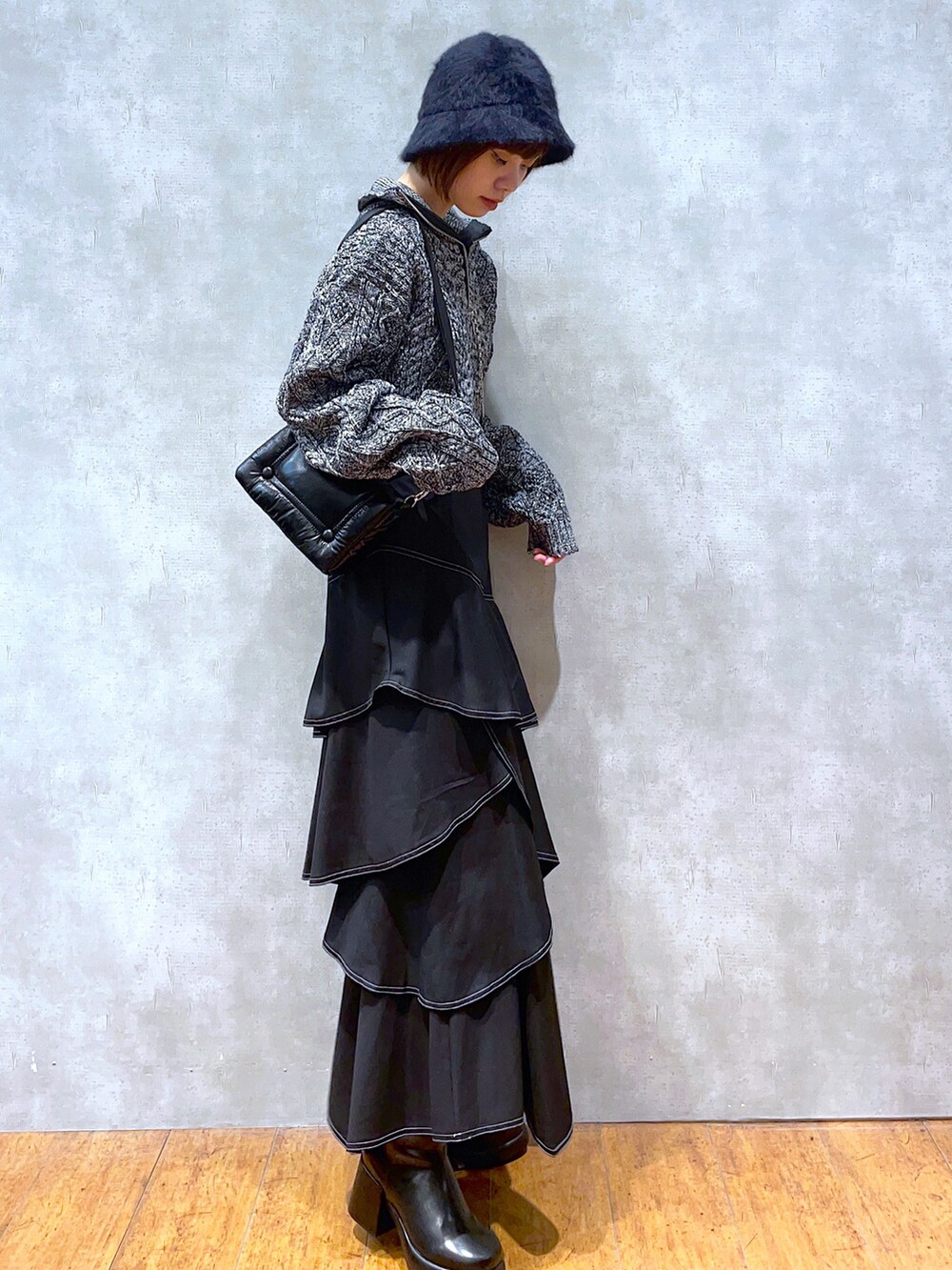 グレー系のニット/セーター、ブラック系のショルダーバッグ、ブラック系のスカートを着用したレディースの秋コーディネートの2枚目の写真