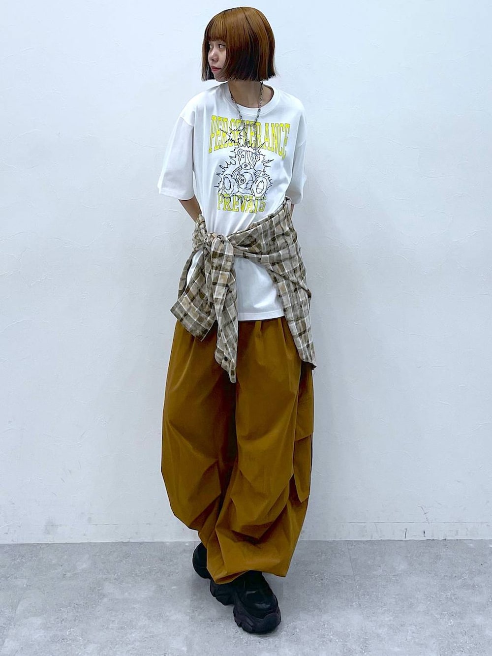 ブラック系のスニーカー、ブラウン系のカーゴパンツ、ホワイト系のTシャツ/カットソーを着用したレディースの夏コーディネートの2枚目の写真