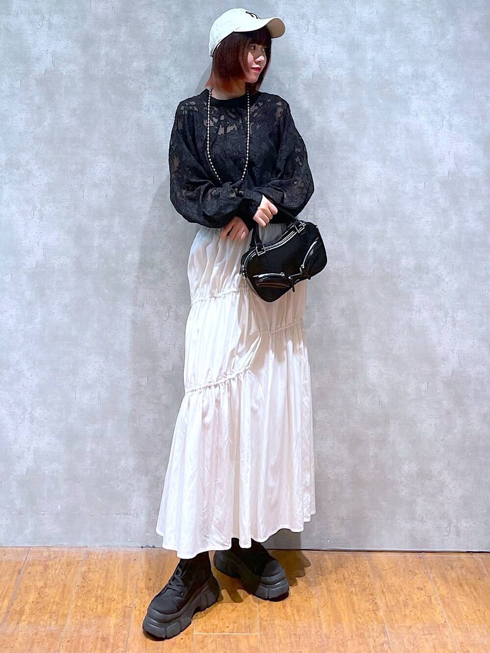 ブラック系のシャツ/ブラウス、ホワイト系のスカート、ブラック系のボストンバッグを着用したレディースの春コーディネートの3枚目の写真