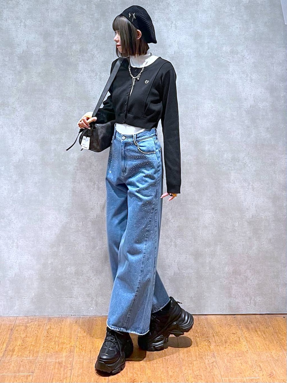 ブラック系のスニーカー、ホワイト系のニット/セーター、ブルー系のデニムパンツを着用したレディースの秋コーディネートの2枚目の写真