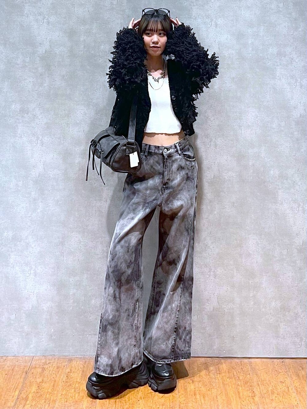 ブラック系のスニーカー、ブラック系のショルダーバッグ、ブラック系のデニムパンツを着用したレディースの秋コーディネートの5枚目の写真