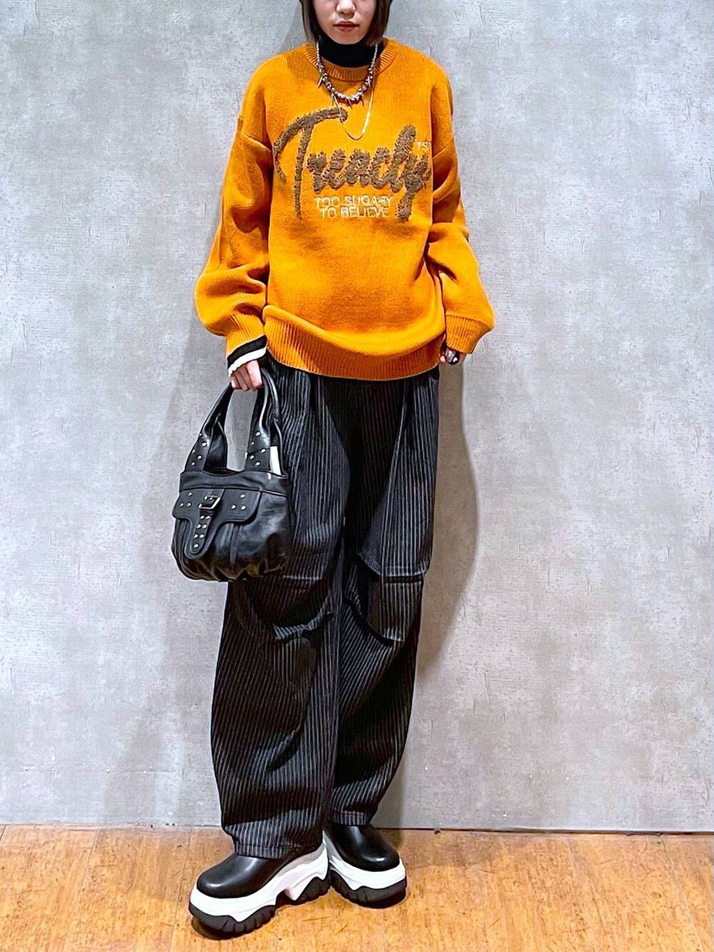 ブラック系のニット/セーター、ブラック系のデニムパンツ、ブラック系のハンドバッグを着用したレディースの秋コーディネートの8枚目の写真