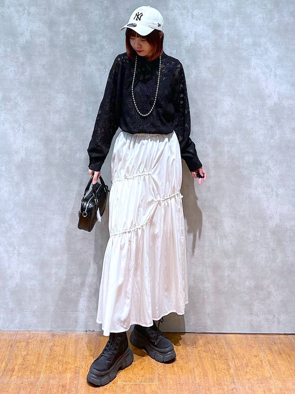 ブラック系のシャツ/ブラウス、ホワイト系のスカート、ブラック系のボストンバッグを着用したレディースの春コーディネートの2枚目の写真