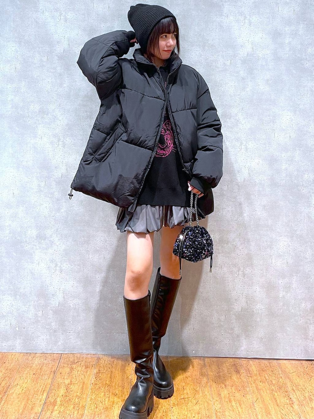 グレー系のスカート、ブラック系のブーツ、ブラック系のダウンジャケット/コートを着用したレディースの冬コーディネートの5枚目の写真