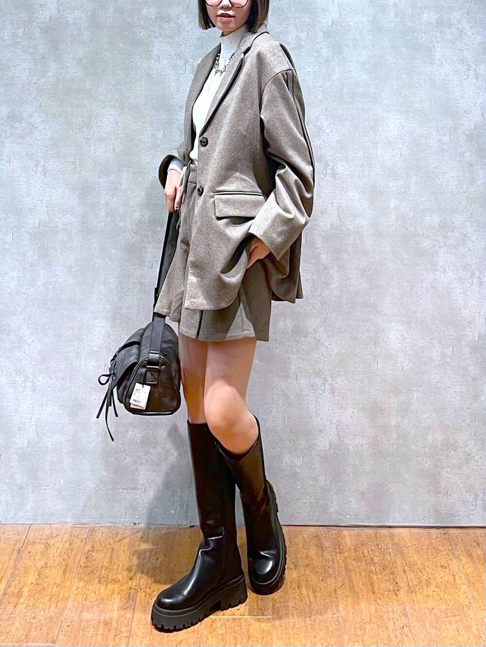 ブラック系のショルダーバッグ、ホワイト系のニット/セーター、ブラック系のブーツを着用したレディースの秋コーディネートの7枚目の写真