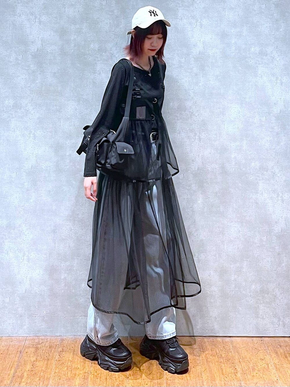 ブラック系のショルダーバッグ、ブラック系のスニーカー、ブルー系のデニムパンツを着用したレディースの春コーディネートの2枚目の写真