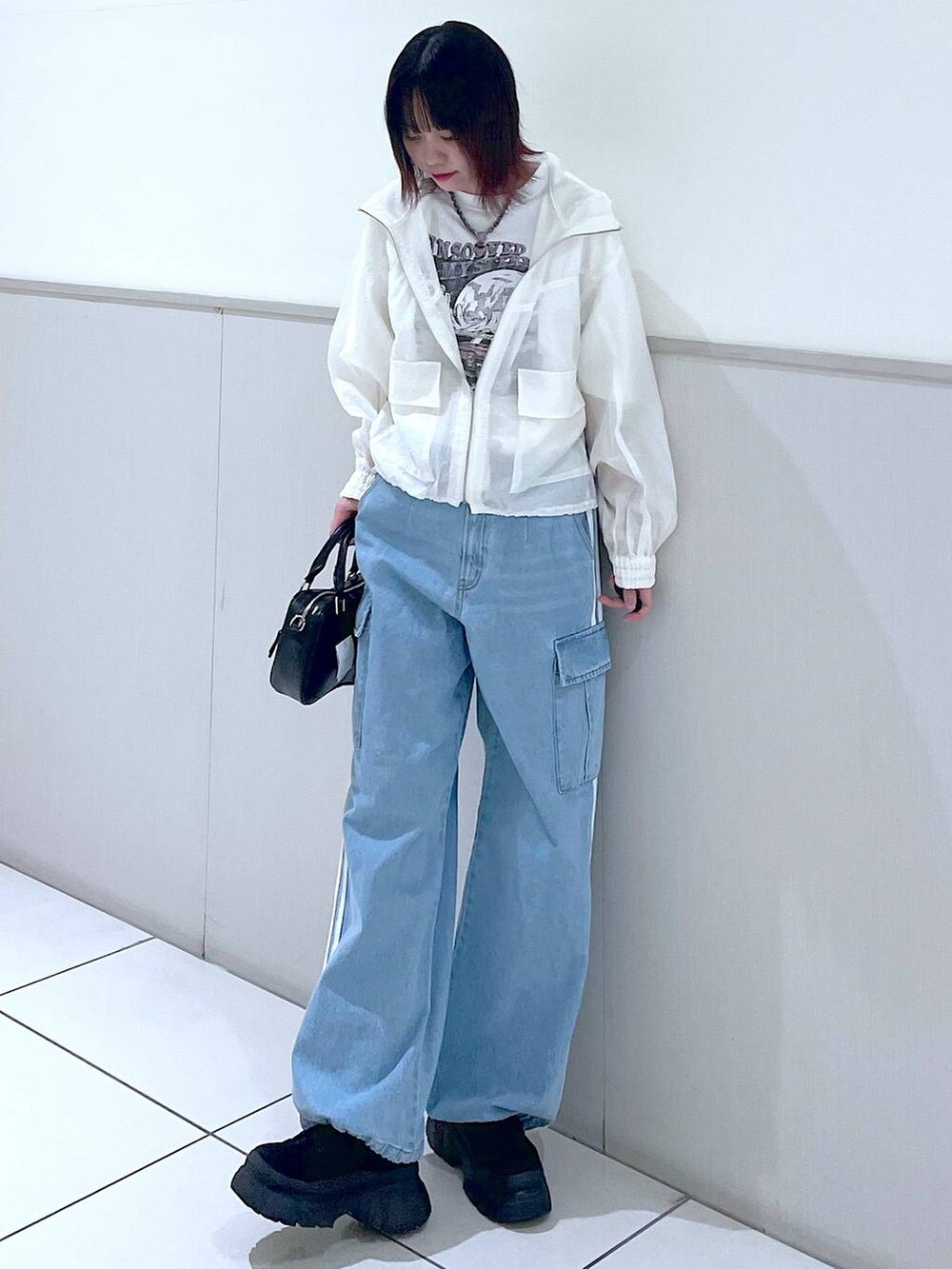 ホワイト系のブルゾン、ブルー系のデニムパンツ、ブラック系のボストンバッグを着用したレディースの春コーディネートの2枚目の写真
