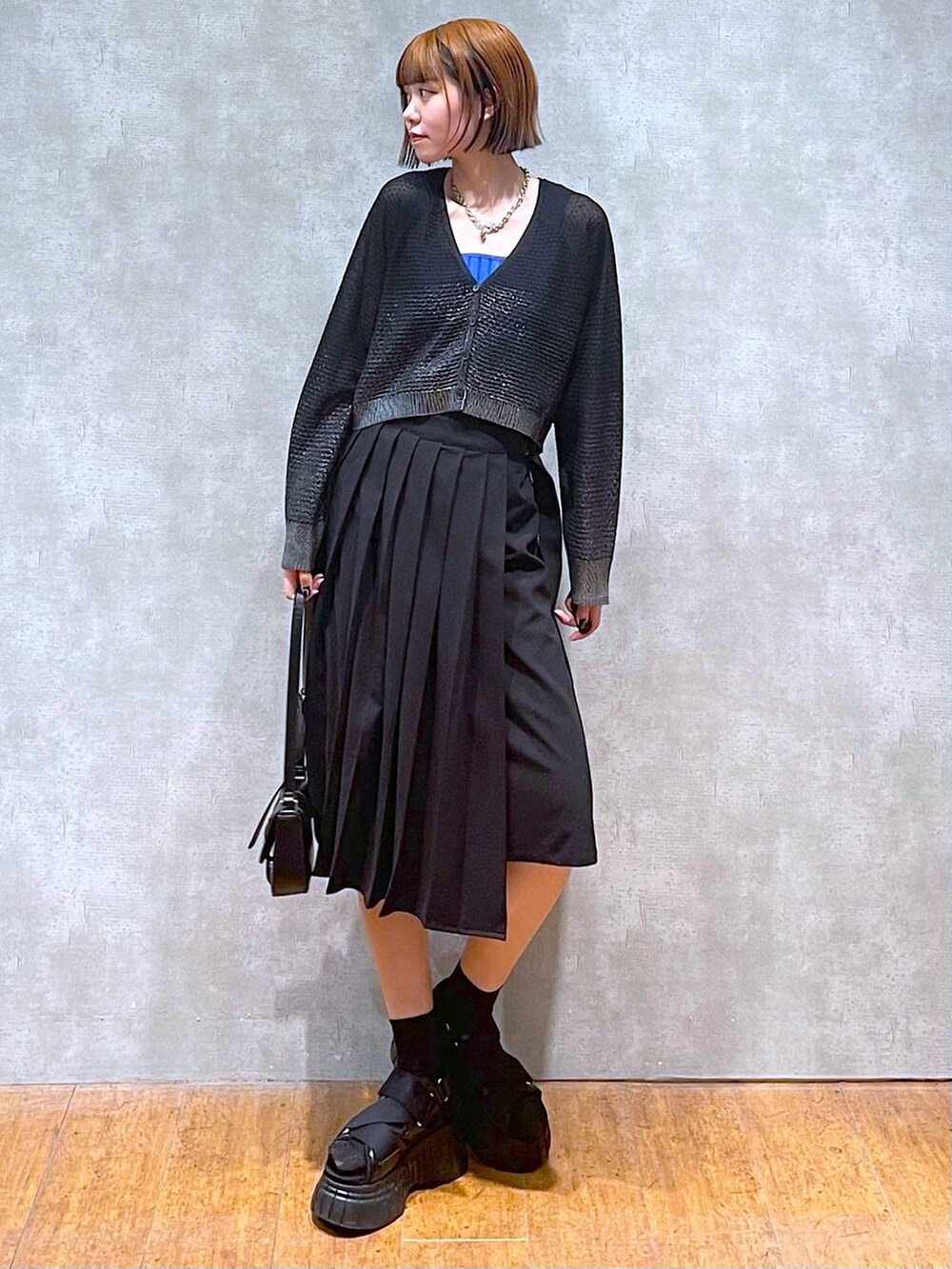 ブラック系のスニーカー、ブルー系のタンクトップ、ブラック系のスカートを着用したレディースの夏コーディネートの3枚目の写真