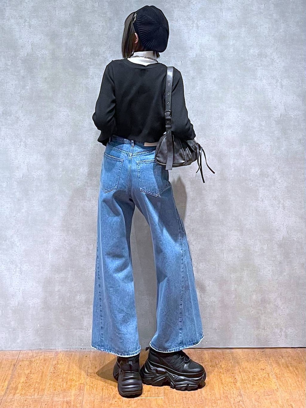 ブラック系のスニーカー、ホワイト系のニット/セーター、ブルー系のデニムパンツを着用したレディースの秋コーディネートの4枚目の写真