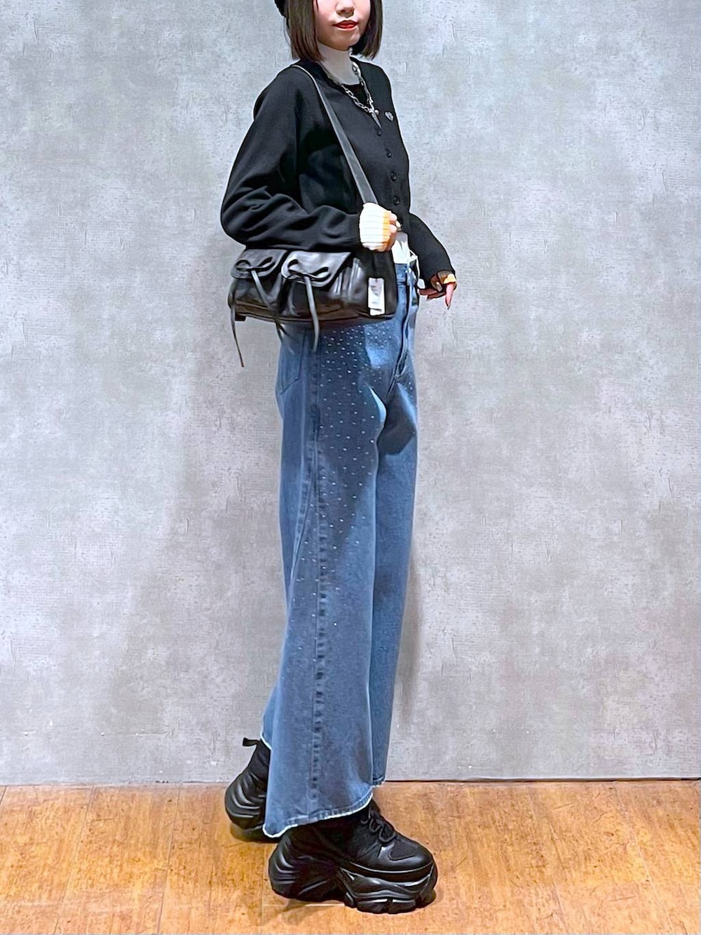 ブラック系のスニーカー、ホワイト系のニット/セーター、ブルー系のデニムパンツを着用したレディースの秋コーディネートの5枚目の写真