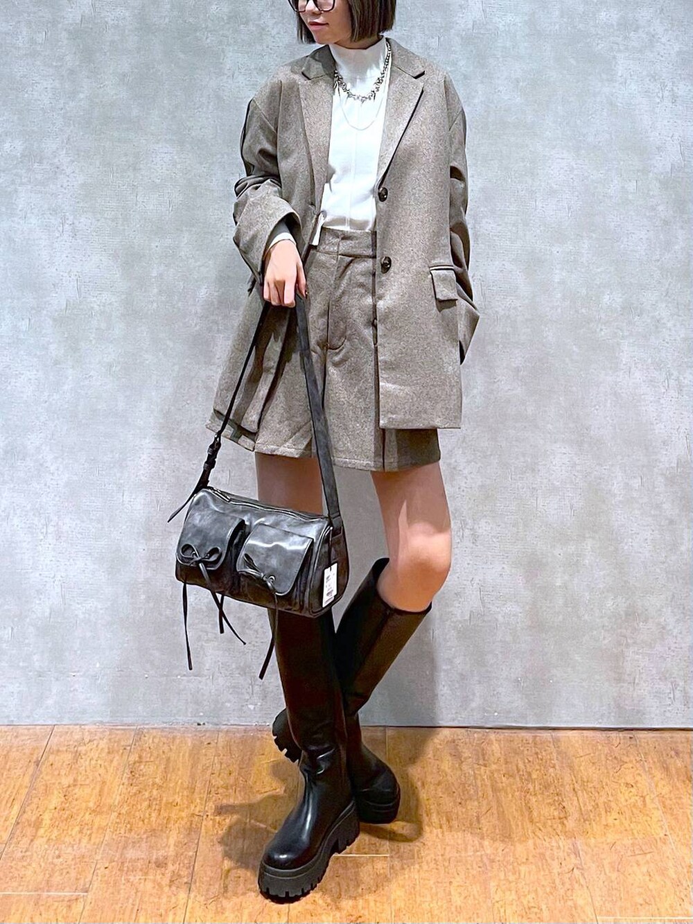 ブラック系のショルダーバッグ、ホワイト系のニット/セーター、ブラック系のブーツを着用したレディースの秋コーディネートの8枚目の写真