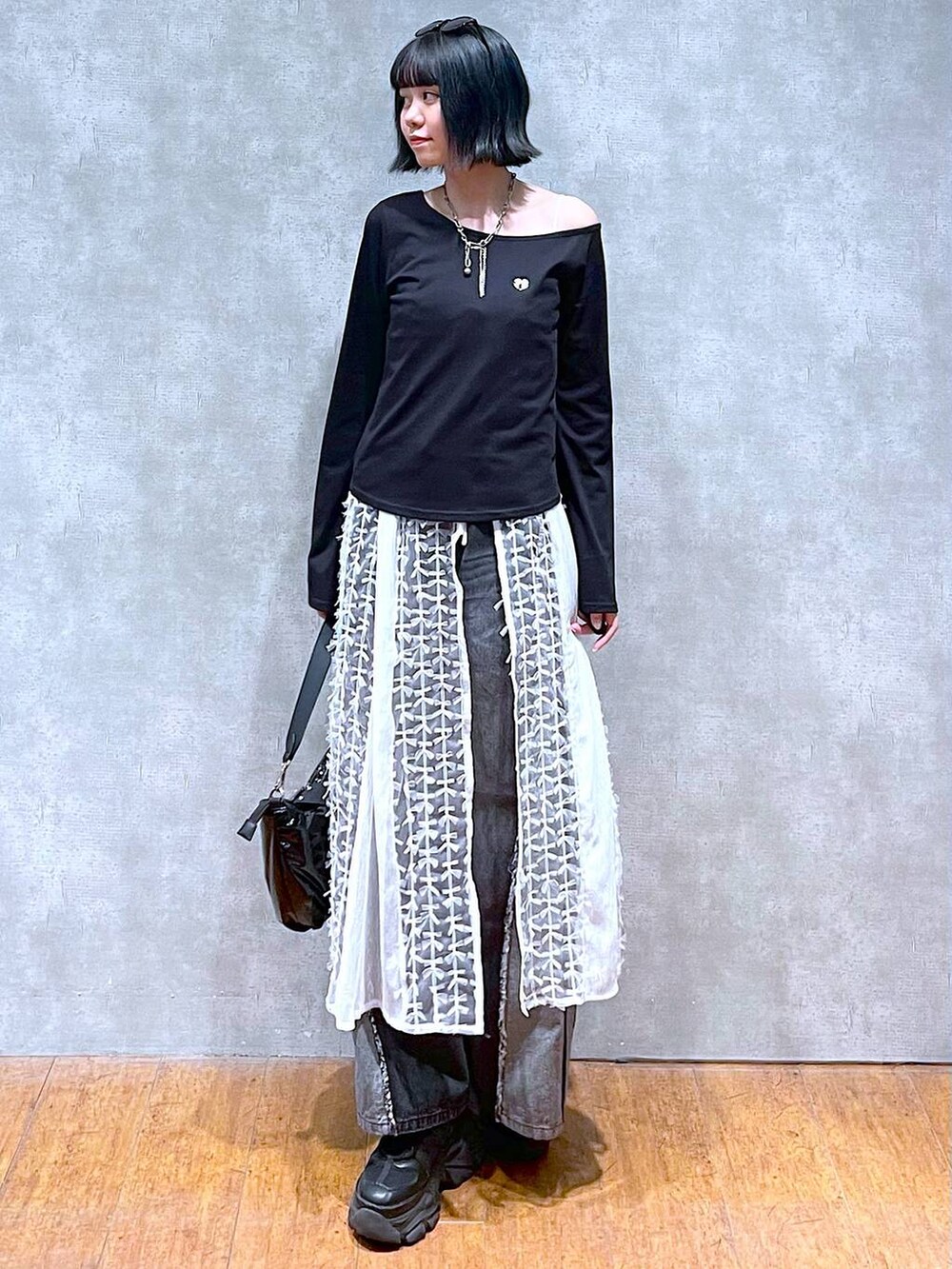 ブラック系のスニーカー、ブラック系のデニムパンツ、ブラック系のショルダーバッグを着用したレディースの夏コーディネートの2枚目の写真