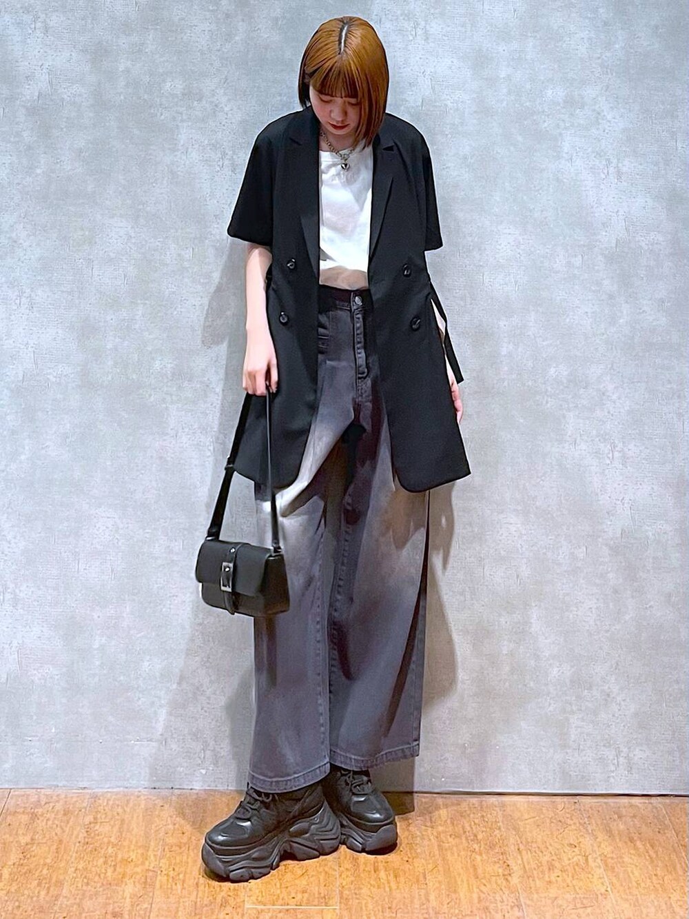 ブラック系のスニーカー、ホワイト系のTシャツ/カットソー、ブラック系のハンドバッグを着用したレディースの夏コーディネートの3枚目の写真