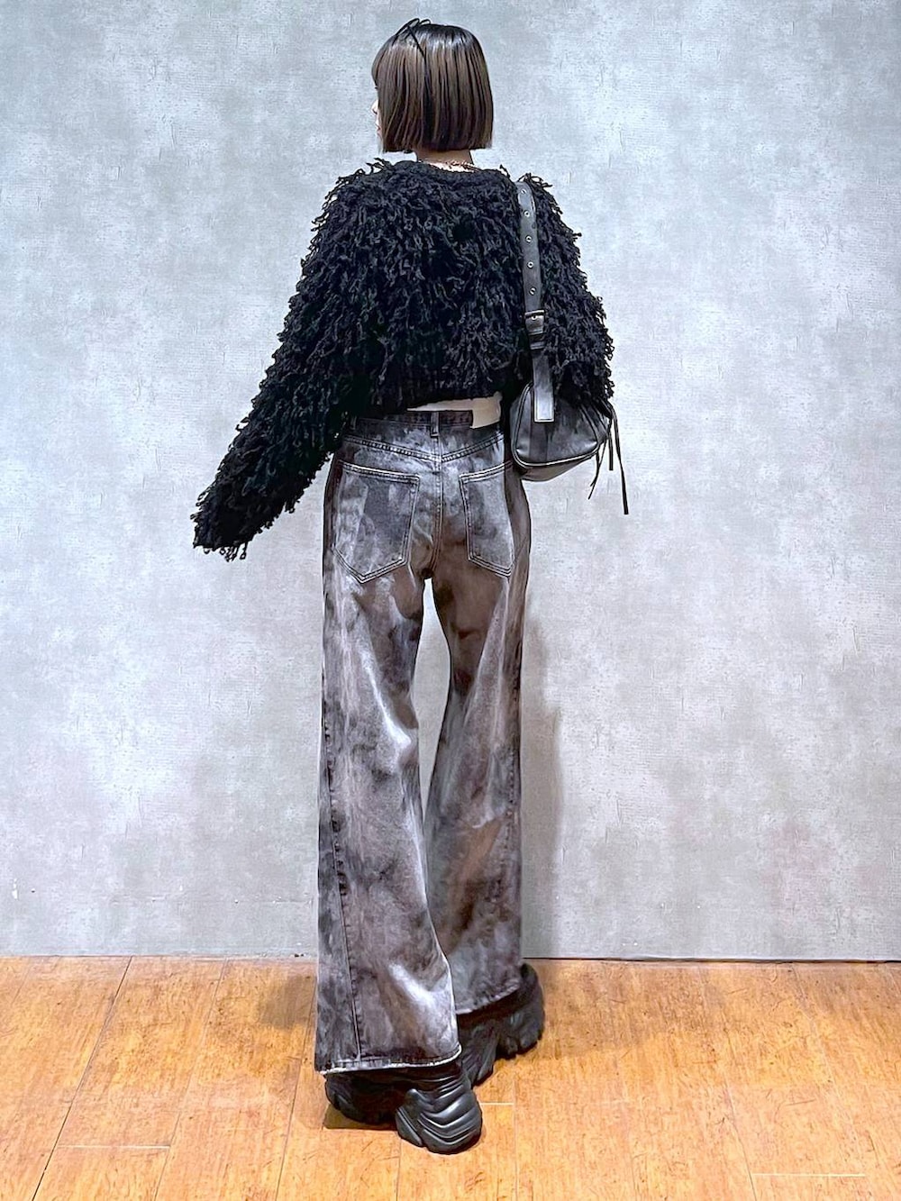 ブラック系のスニーカー、ブラック系のショルダーバッグ、ブラック系のデニムパンツを着用したレディースの秋コーディネートの4枚目の写真