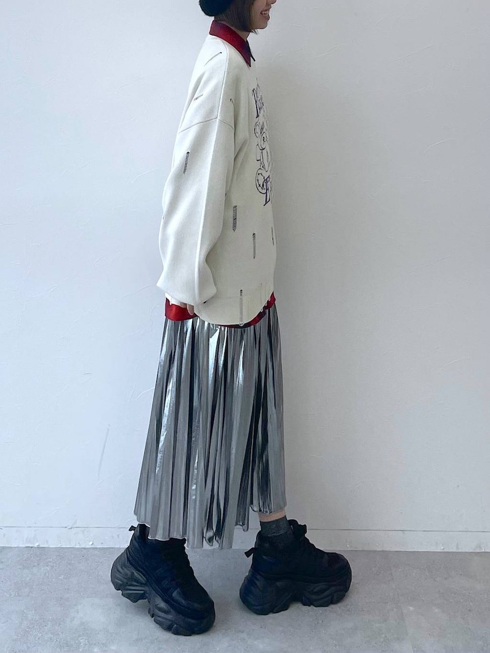 ブラック系のスニーカー、グレー系のスカート、ホワイト系のニット/セーターを着用したレディースの秋コーディネートの4枚目の写真