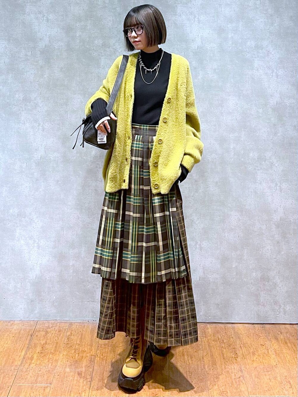 ブラック系のニット/セーター、ブラック系のショルダーバッグ、ブラウン系のブーツを着用したレディースの秋コーディネートの8枚目の写真