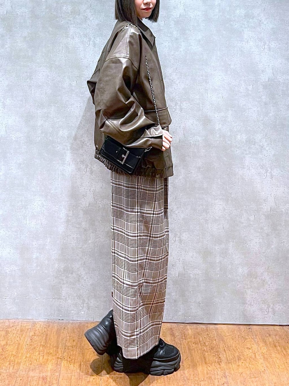 ブラック系のスニーカー、ホワイト系のニット/セーター、ベージュ系のスラックスを着用したレディースの秋コーディネートの4枚目の写真