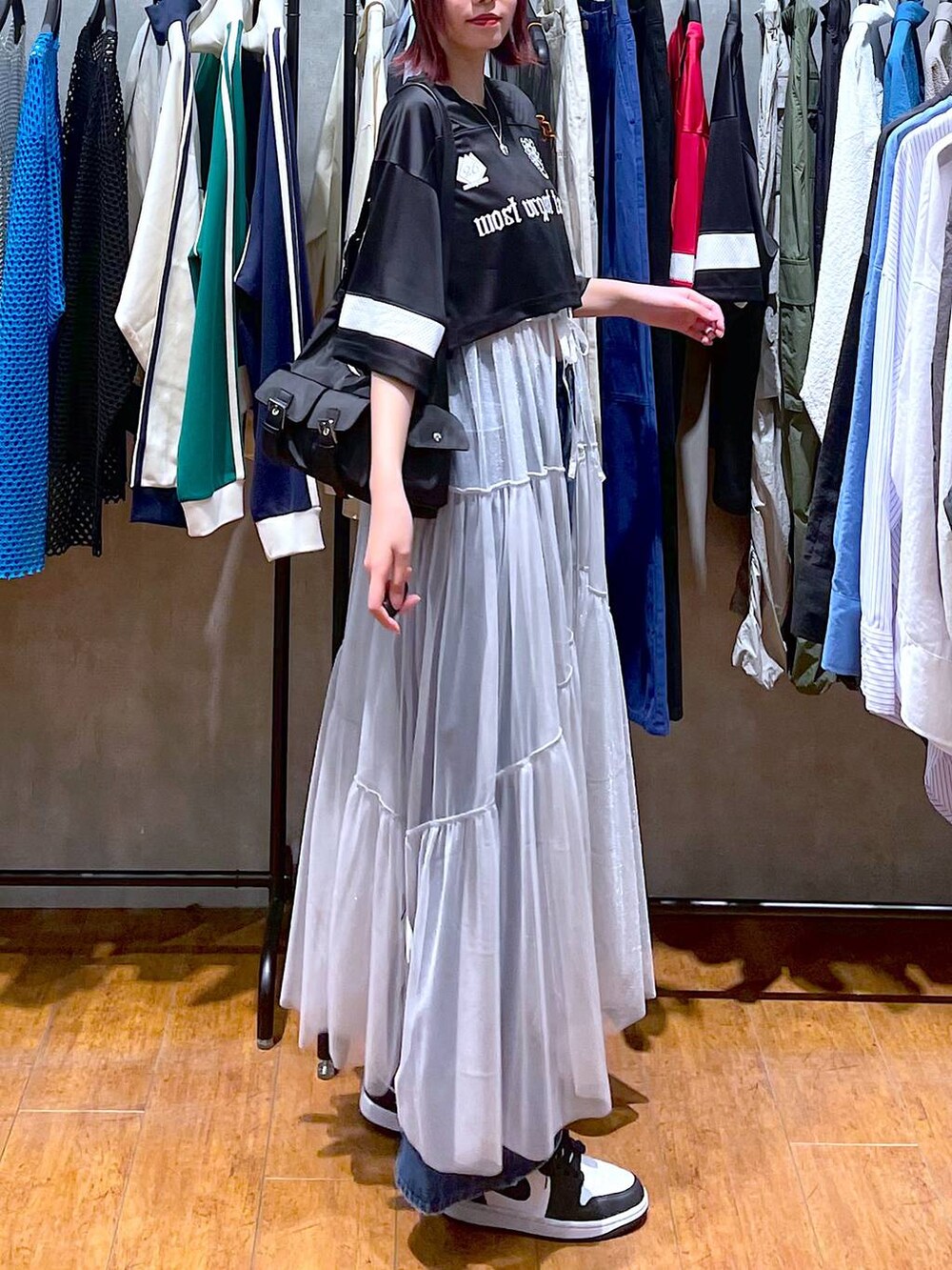 ブラック系のショルダーバッグ、ブルー系のデニムパンツ、ホワイト系のワンピースを着用したレディースの春コーディネートの4枚目の写真