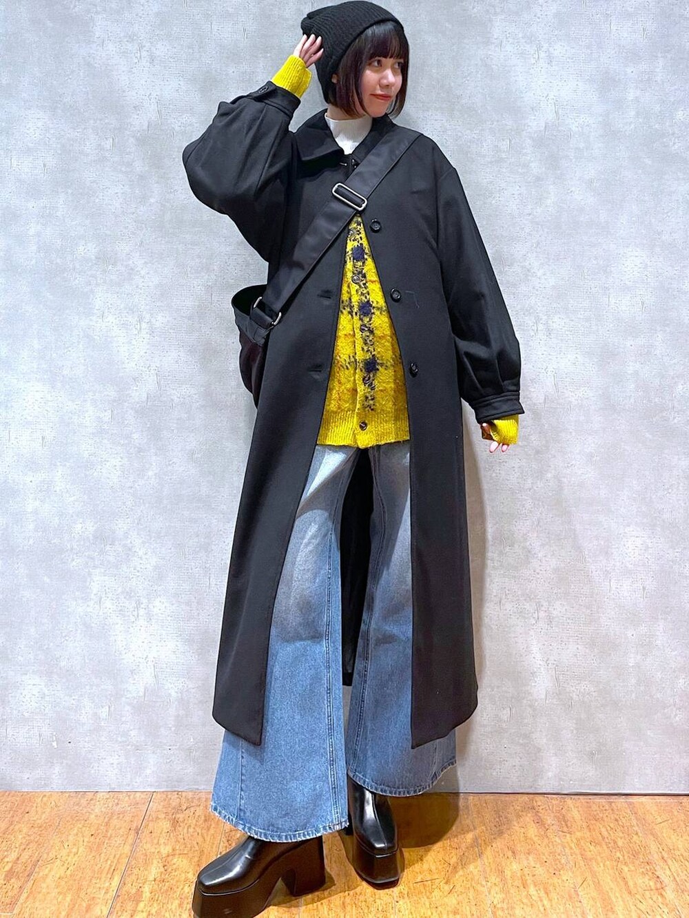 ブラック系のチェスターコート、ブルー系のデニムパンツ、イエロー系のカーディガン/ボレロを着用したレディースの冬コーディネートの4枚目の写真