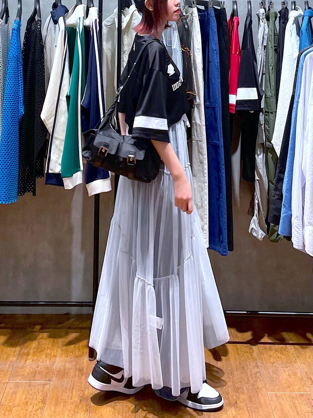 ブラック系のショルダーバッグ、ブルー系のデニムパンツ、ホワイト系のワンピースを着用したレディースの春コーディネートの6枚目の写真