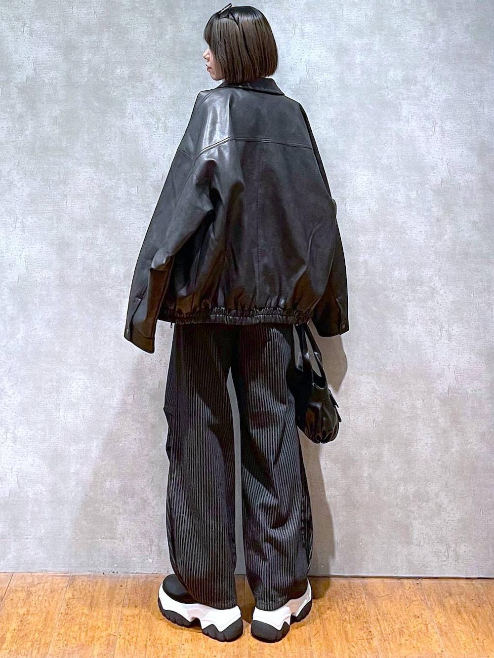 ブラック系のブルゾン、ブラック系のデニムパンツ、ブラック系のハンドバッグを着用したレディースの秋コーディネートの6枚目の写真