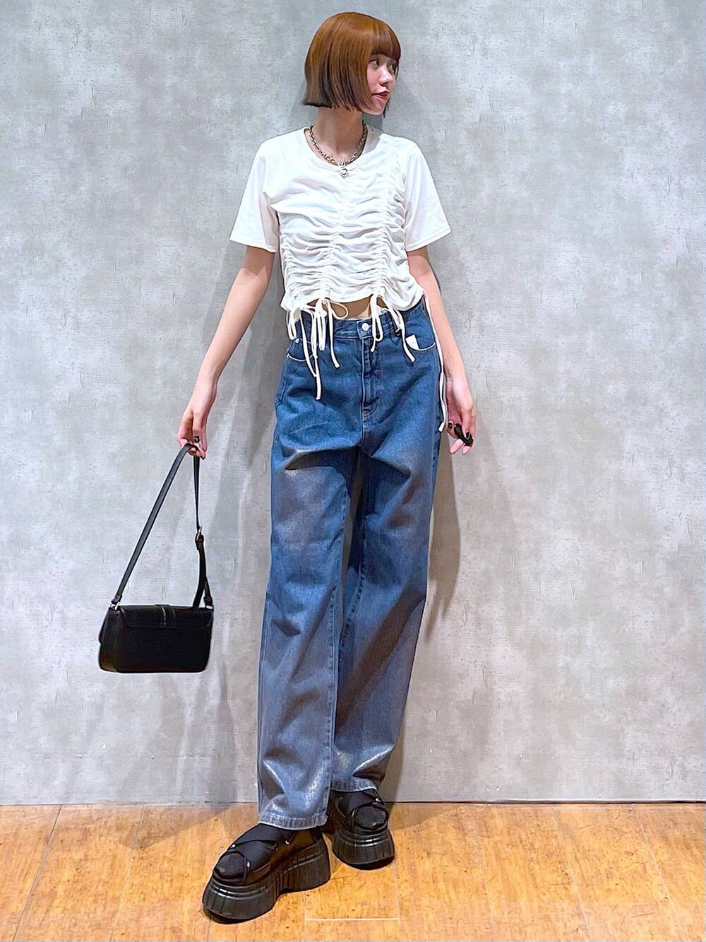 ブラック系のスニーカー、ブラック系のハンドバッグ、ホワイト系のTシャツ/カットソーを着用したレディースの夏コーディネートの5枚目の写真