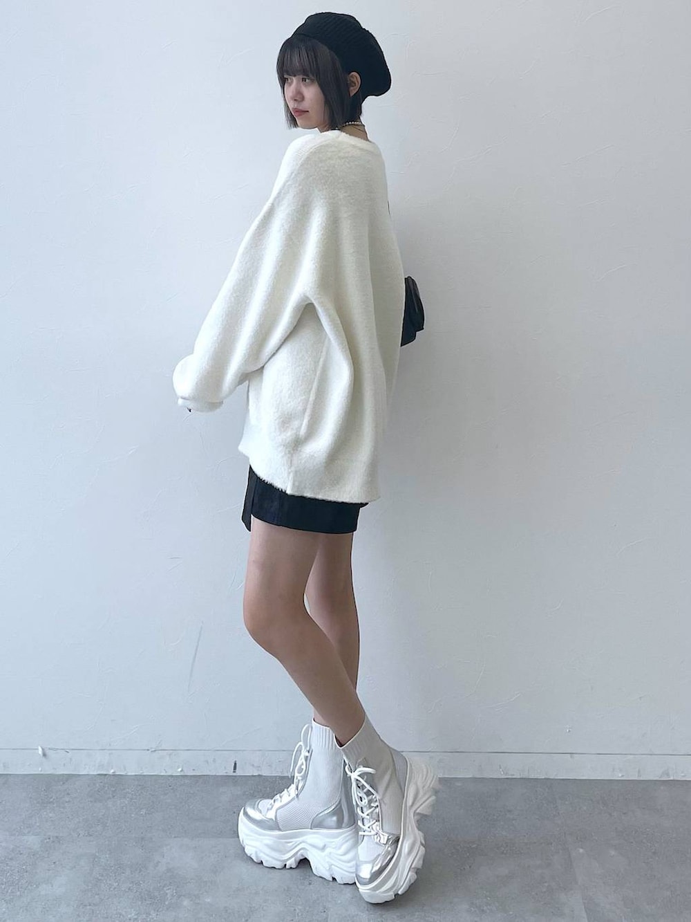 ホワイト系のブーツ、ブラック系のショルダーバッグ、ホワイト系のニット/セーターを着用したレディースの秋コーディネートの5枚目の写真