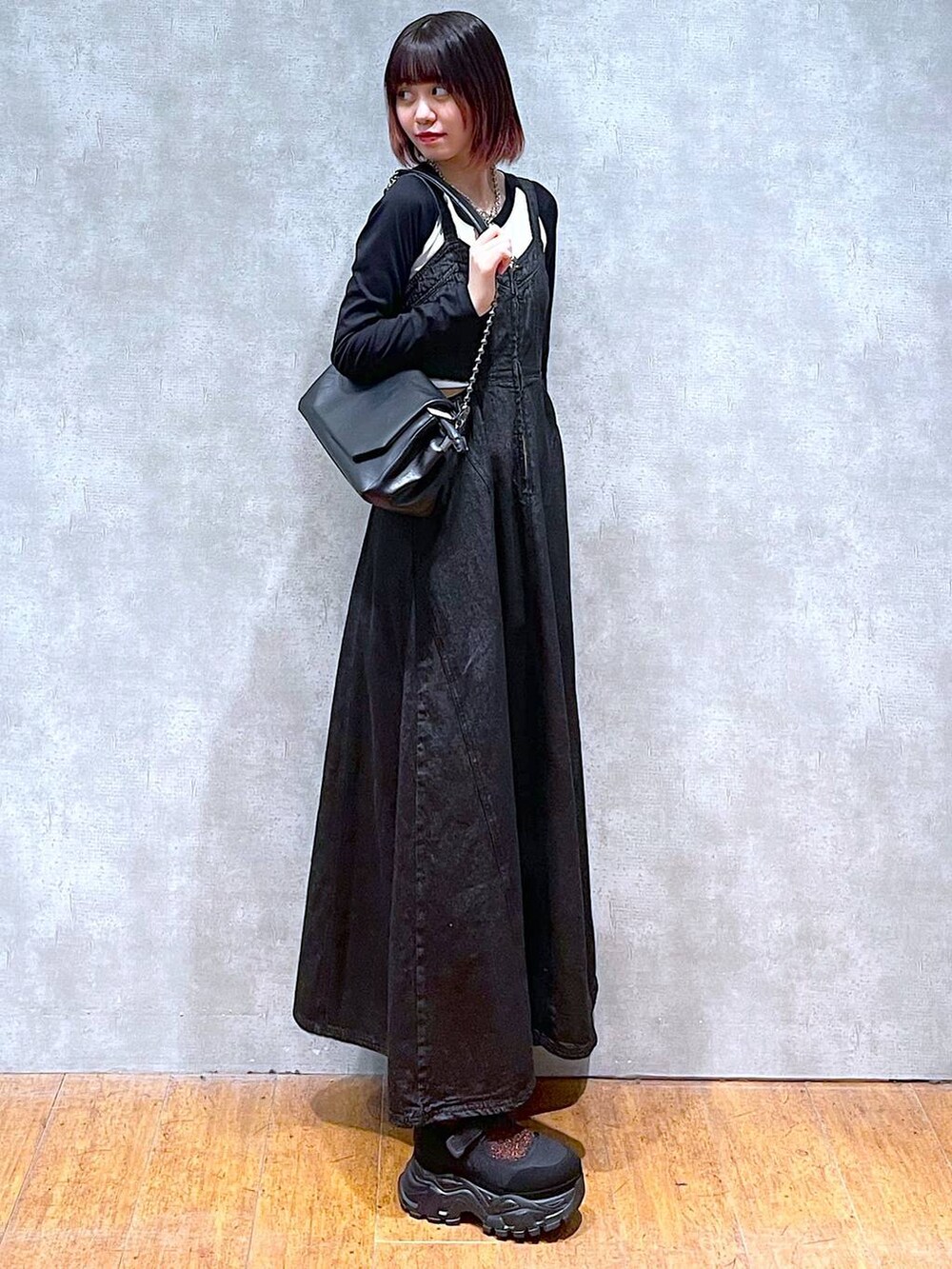 ブラック系のショルダーバッグ、ホワイト系のTシャツ/カットソー、ブラック系のワンピースを着用したレディースの春コーディネートの2枚目の写真