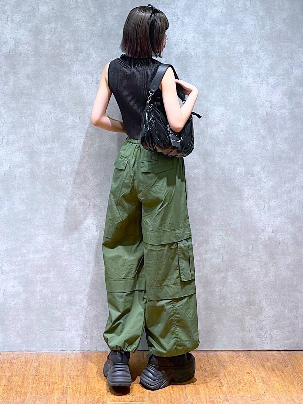 ブラック系のスニーカー、ブラック系のニット/セーター、グリーン系のその他パンツを着用したレディースの夏コーディネートの5枚目の写真